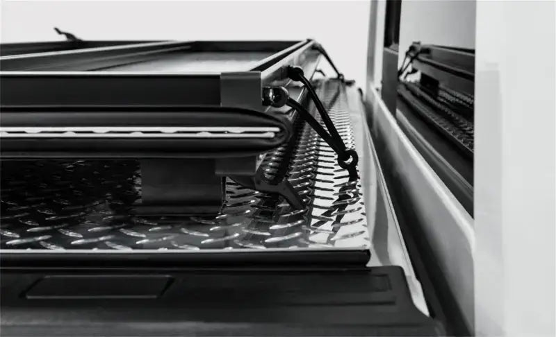 Black diamond plate Access LOMAX tri-fold truck bed cover with securing straps