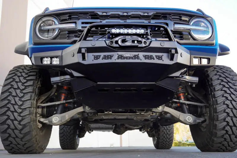 DV8 Offroad Spec Series Front Bumper mounted on a 2021-2023 Ford Bronco with rugged tires and winch setup, showcasing its durability and low-profile design for rock crawling.