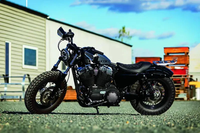 Black motorcycle with Kuryakyn Thresher Grips in a parking lot, featuring dual cable setup for superior control and comfort.