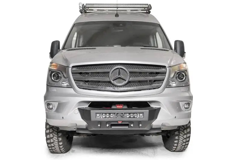 Silver Mercedes Sprinter van with Fab Fours winch mount, rugged tires and roof light bar