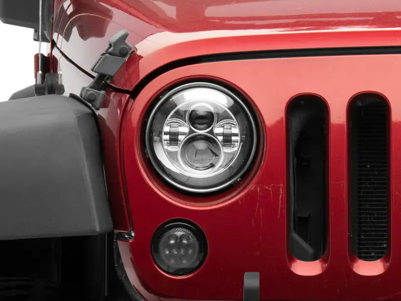 Red Jeep headlight showcasing Raxiom LED Daymaker headlights for Jeep Wrangler TJ/JK