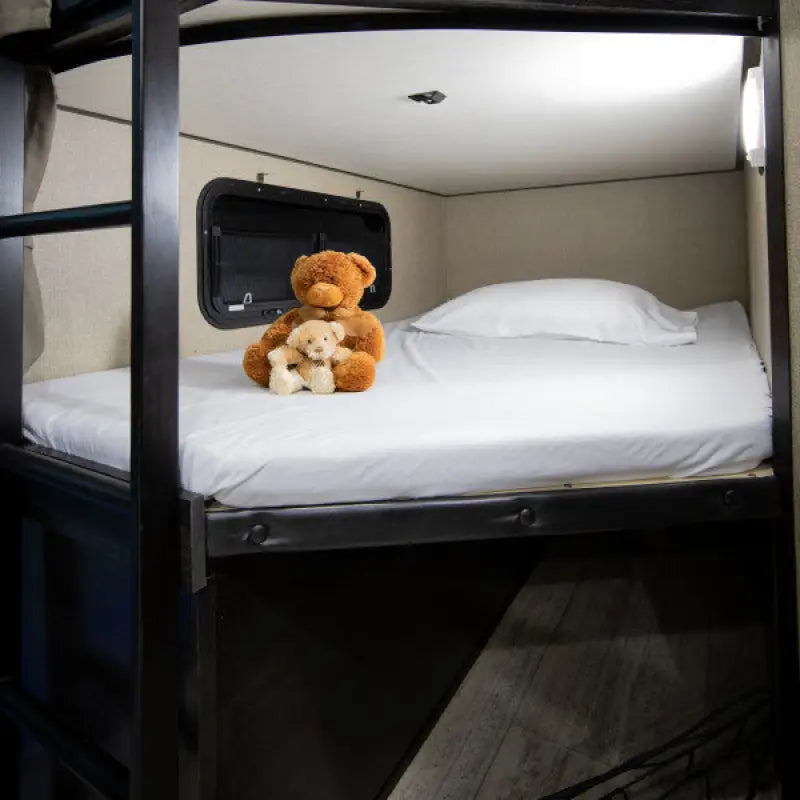 Cozy bunk bed setup with white linens and stuffed teddy bears, showcasing the comfort and luxury of Thomas Payne Adjustable Microfiber furniture by Lippert Comp.