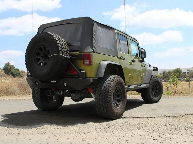 Green Jeep Wrangler with oversized tires featuring afe rebel series Cat-Back exhaust system