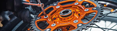 Orange and silver rear steel sprocket being worked on for BikeMaster Suzuki 428 51T