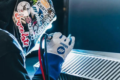 Welder with helmet and gloves working on high performance plate intercooler core