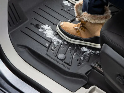 Black floor liner molded fit with snow, channels, and WeatherTech logo suitable for cars