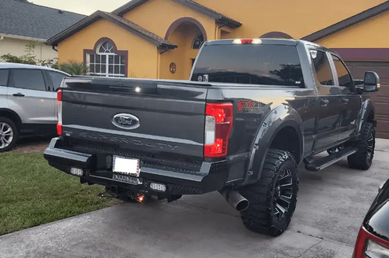 FS17-T4150-1 Fab Fours rear bumper installed on Ford F250 Super Duty in a driveway, showcasing robust construction and sleek design.