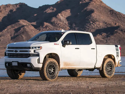 White Chevrolet Silverado truck with ICON 2019+ GM 1500 Stage 4 Suspension System parked in desert terrain.