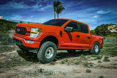 Orange Ford F150 4WD pickup truck with ICON 21-23 Coilover Kit and 3in lift