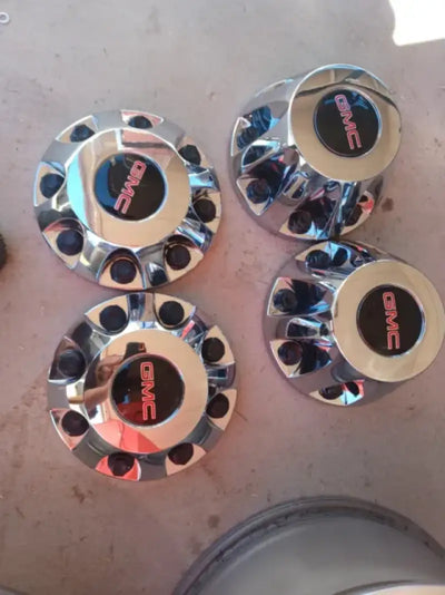 Polished chrome center caps with GMC logo, designed for Ford vehicles, enhancing wheel aesthetics.