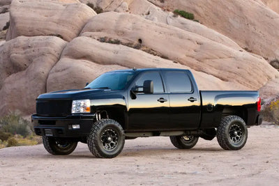 Black truck equipped with K1064 Fabtech Leveling Kit Suspension parked in a rocky desert terrain.
