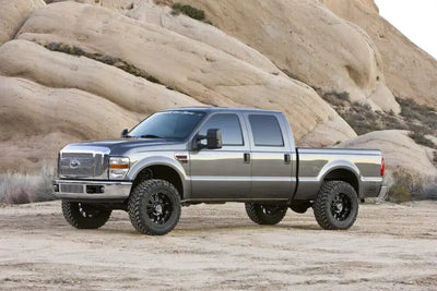 "Truck equipped with K2062 Fabtech Lift Kit Suspension showcasing enhanced ground clearance and off-road capability in a rugged desert terrain"