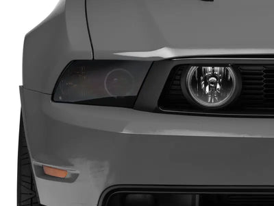Gray car front with tinted headlight showcasing Raxiom LED Halo Fog Lights for Mustang