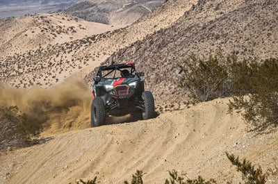 Off-road vehicle kicking up dust with Daystar HCR Suspension on rugged trails